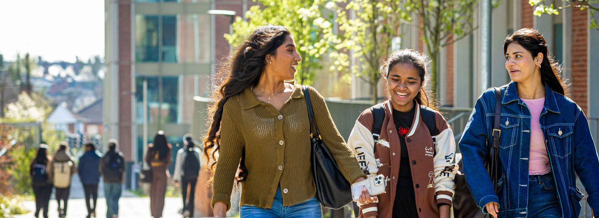 Three women walking, talking and smiling.