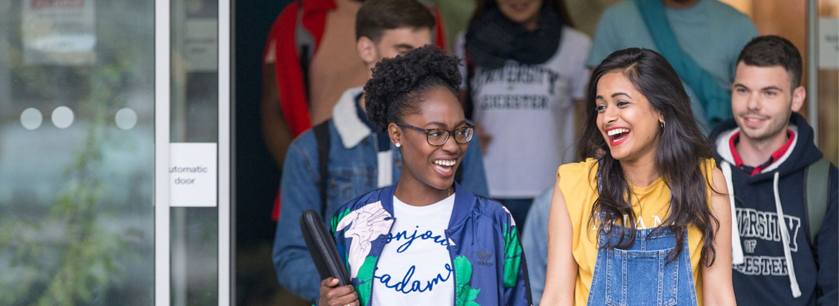 Students leaving a University of Leicester building, chatting and laughing