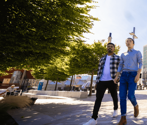4 students walking outside library on sunny day