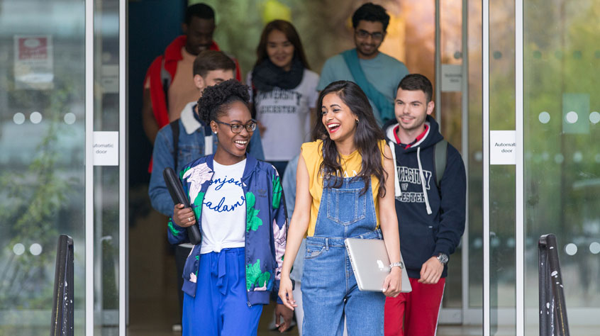 Students leaving a University of Leicester building, chatting and laughing