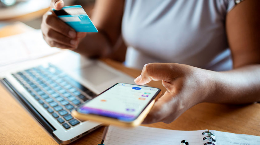 Person on their phone, holding a credit card and making a purchase