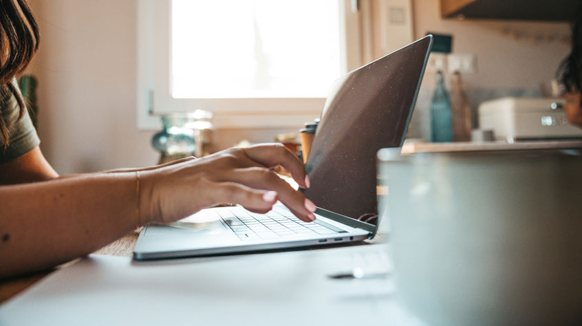 Person sat a kitchen table working on their laptop