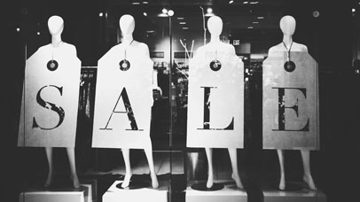 Four mannequins lined up with boards which spell out the word sale.