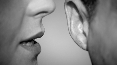 closeup of a person whispering into another person's ear