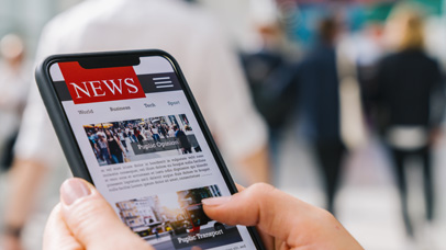 A person holding a mobile phone looking at a news landing page