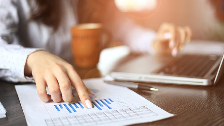 Woman using laptop and pointing at chart