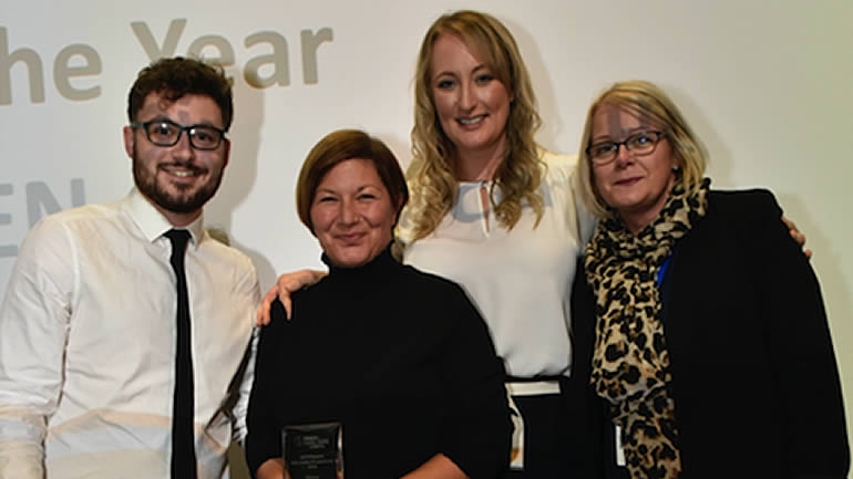 People showing off an award at a ceremony