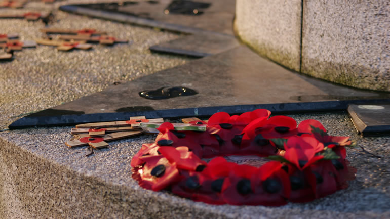 A poppy wreath at the foot of a war memorial