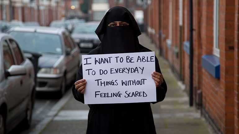 Woman posing with sign about hate crime