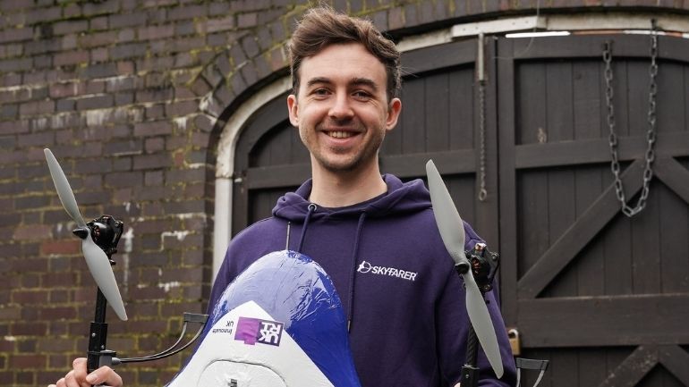 Elliot Parnham, Founder and CEO at Skyfarer, holds a drone with a wingspan larger than a human's outstretched arms.