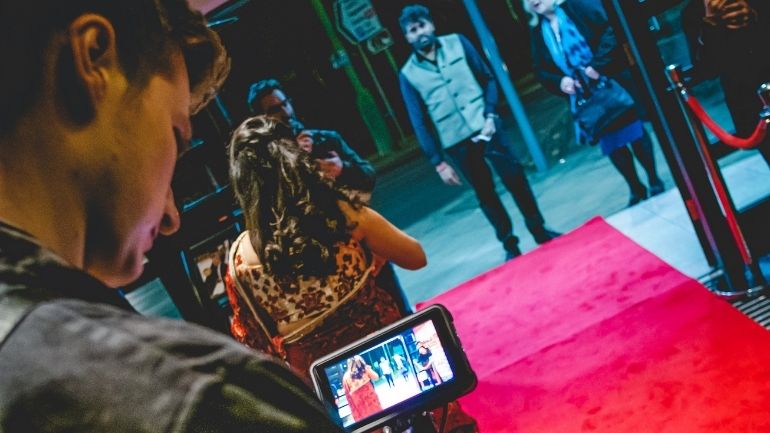 A man operates a camera looking down a red carpet at film premiere of My Niece’s Big Fat Delhi Wedding.