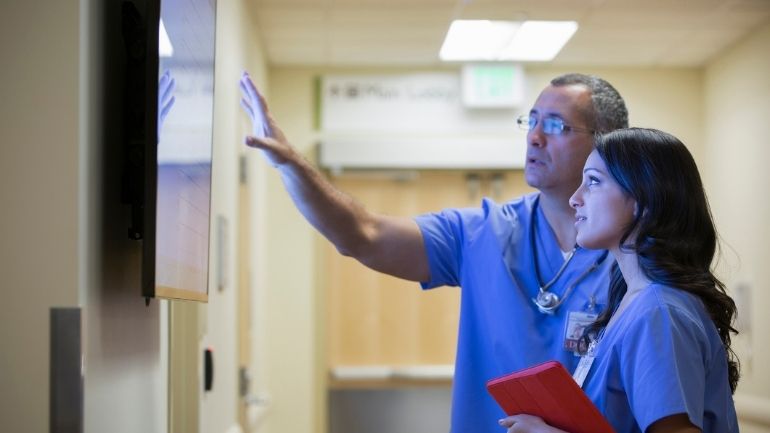 Two healthcare colleagues study results on a screen.