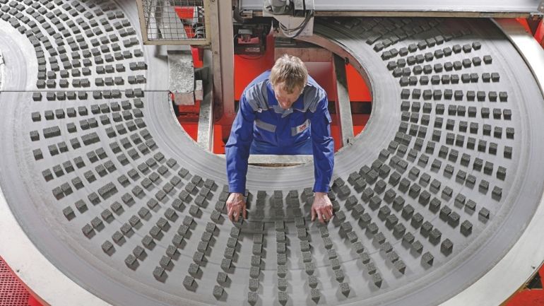A factory worker oversees a production line for advanced ceramics.