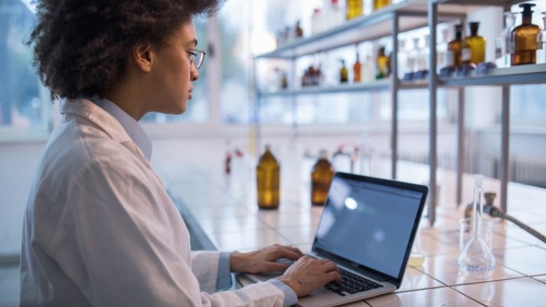 A Black researcher uses a laptop computer in a lab.
