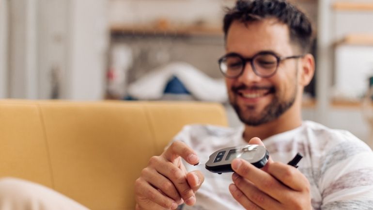 A man performs a handheld blood sugar test at home.