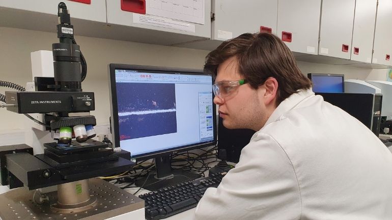 Sean Scott conducting research in a lab using a microscope and computer.