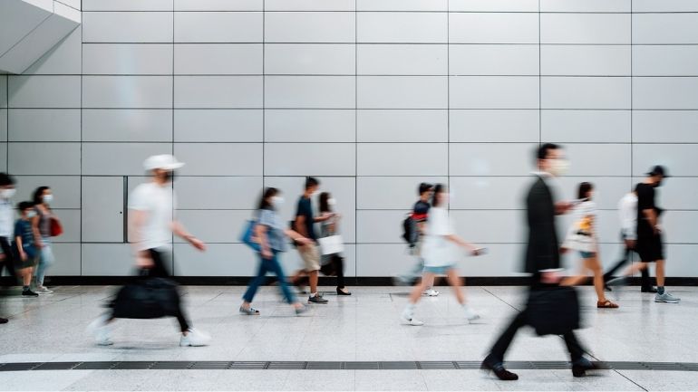 A group of people moving in an airport, wearing protective face coverings.