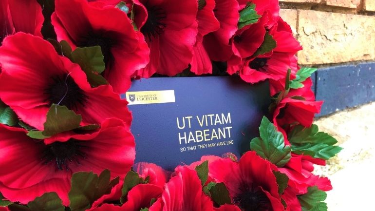 A poppy wreath laid outside the Fielding Johnson Building, with University motto 'Ut Vitam Habeant'.