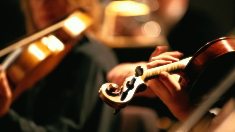 Close up of two musicians playing violins.