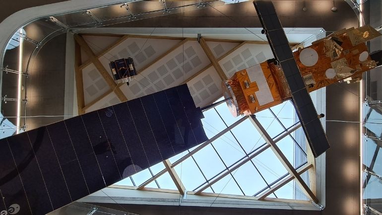View from directly beneath one medium-sized and one small satellite hung from the ceiling of the Space Park Leicester atrium.