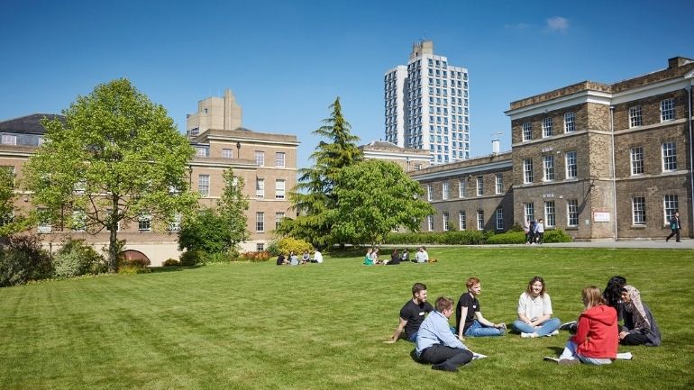 A group of students sat on grass in front of the Fielding Johnson Building.