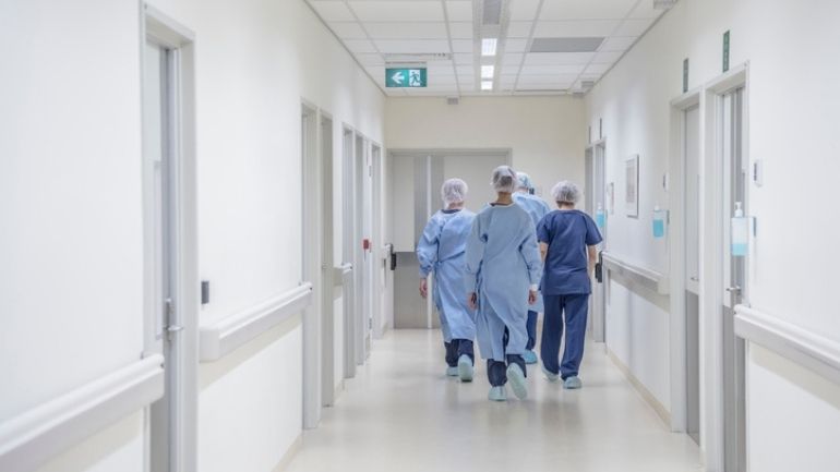 A group of health workers wearing PPE walk down a corridor.