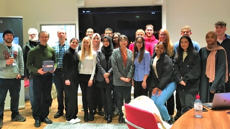 A group of Mathematics students, tutors and industry representatives in a classroom.