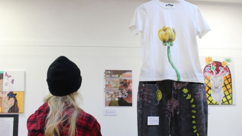 A student, with their back to the camera, looks at pieces of artwork including clothing on a mannequin as part of an exhibition at the Attenborough Arts Centre.