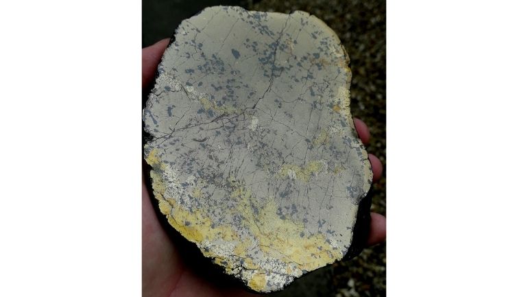 A piece of nickel ore held in a researcher's hand.