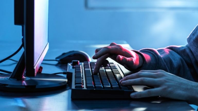 A person using a computer keyboard in low light.