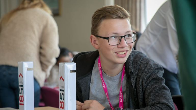 A school-age student wearing a Pathways lanyard takes part in a group activity.