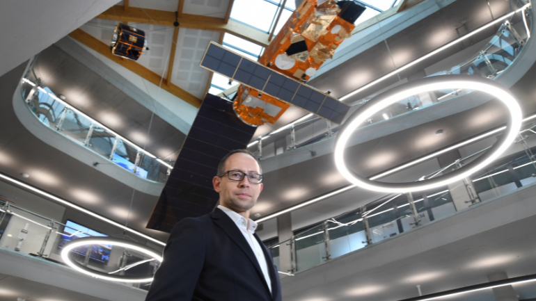 Professor Richard Ambrosi standing in front of a space satellite