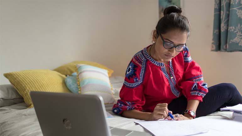 Student sitting on a bed studying