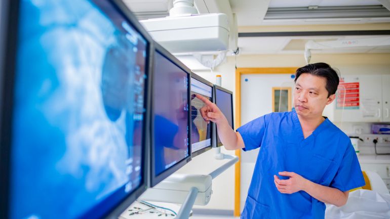 Prof Andre Ng pointing at an electronic display in a lab