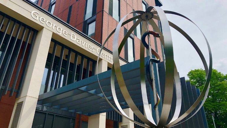 Rod of Asclepius sculpture in front of the George Davies Centre on the University of Leicester campus.