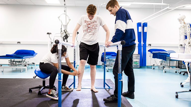 A student leads a physiotherapy clinic session overseen by staff member