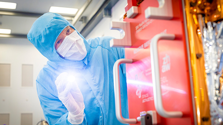 A scientist examines the Soft X-ray Imager (SXI) at Space Park Leicester, prior to handover.