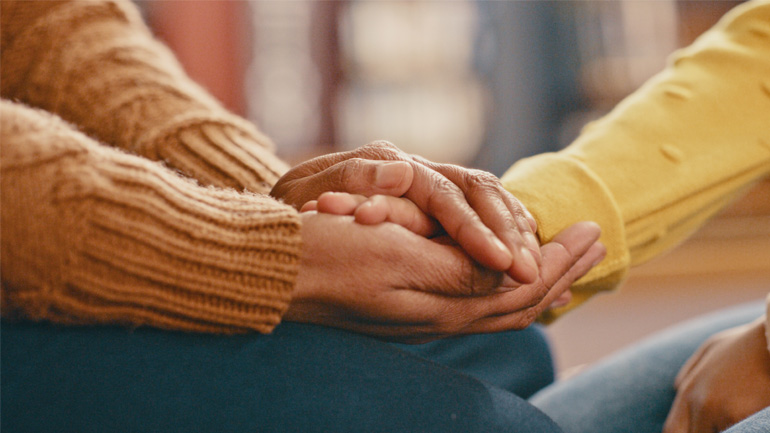 One person clasps another persons hand in support