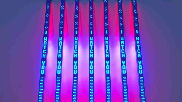 Seven vertical light strips omitting blue and red light reading "I WATCH YOU" 