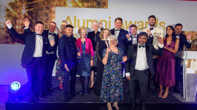 group of alumni award winners celebrating on a stage
