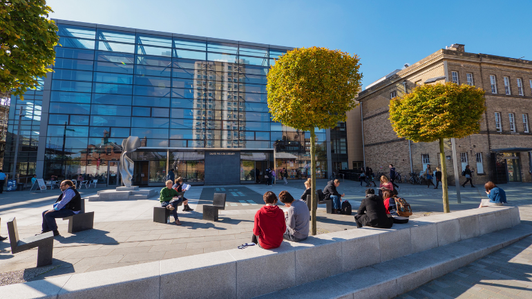 Students sitting in sunlit Centenary Sqaure on campus
