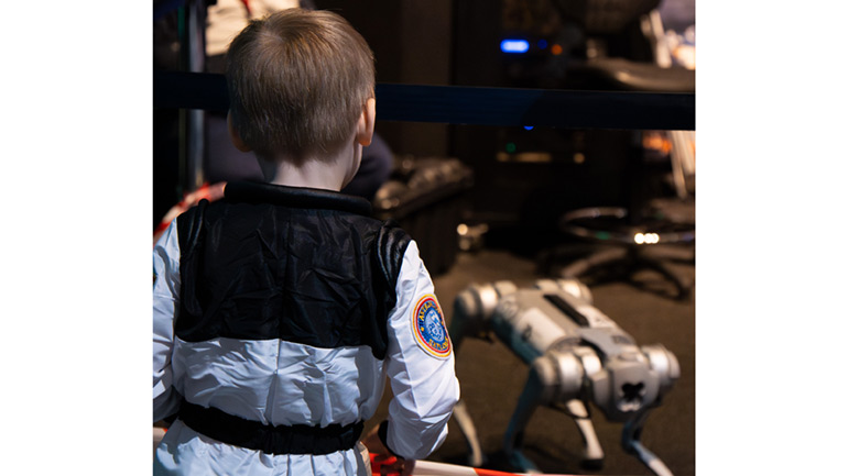 A young visitor watches the DriverLeics robot dog.