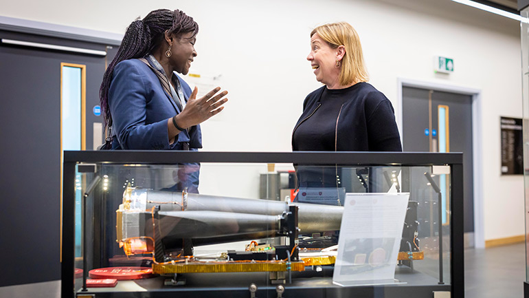 Dr Maggie Aderin-Pocock speaks to Professor Emma Bunce next to a model of the MIXS instrument.