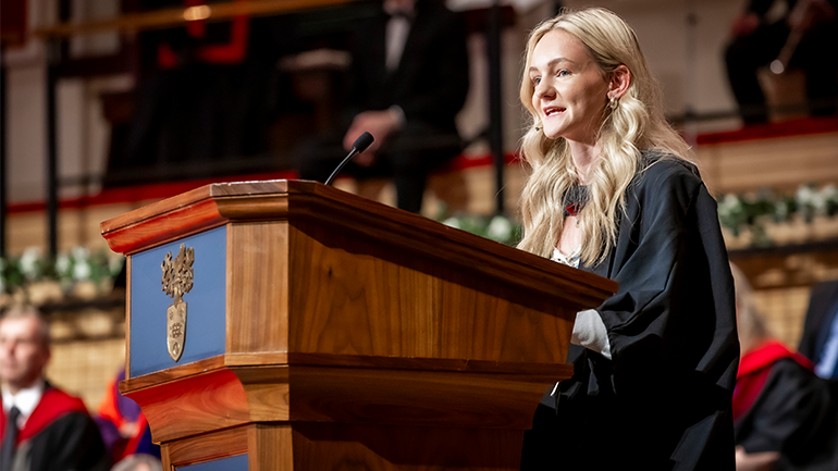 Ella Bailey speaking at a lectern during her graduation ceremony