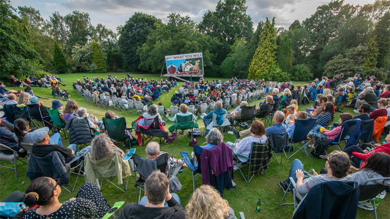 Audience watching a performance of Twelfth Night in a park.