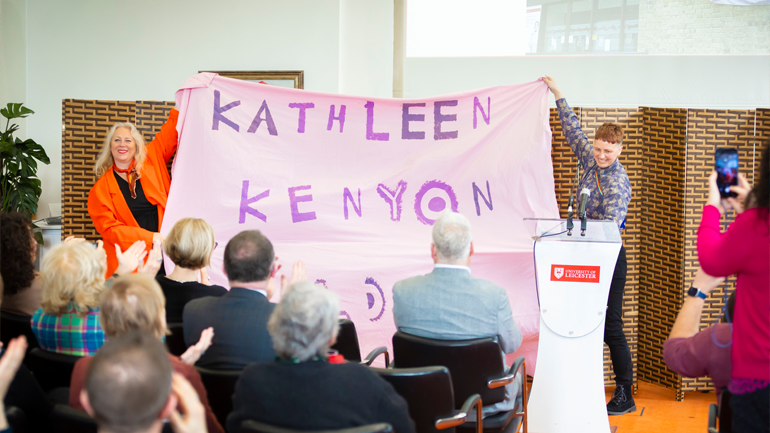 Professor Teela Sanders and Dr Alice Samson hold a purple banner with "Kathleen Kenyon" painted on it.