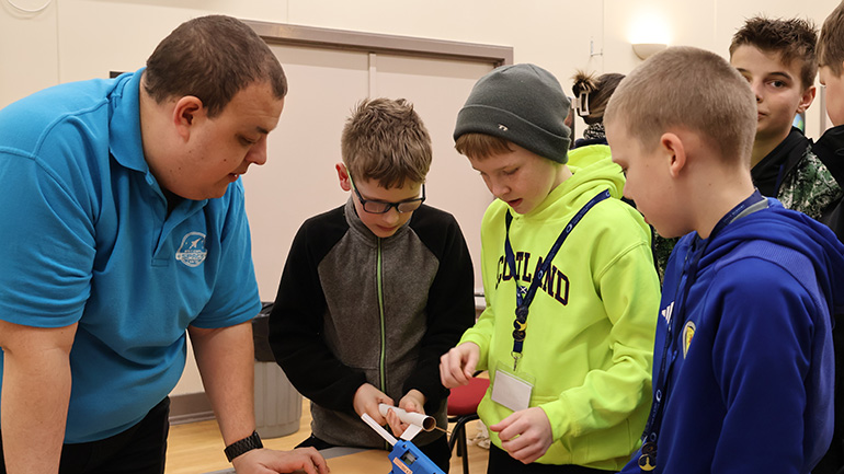 Josh Barker helps some of the students to glue fins onto the rockets they built ahead of launching them.