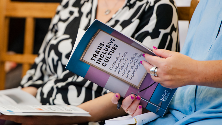 A person holds a copy of Trans Inclusive Culture at its launch event in 2023.