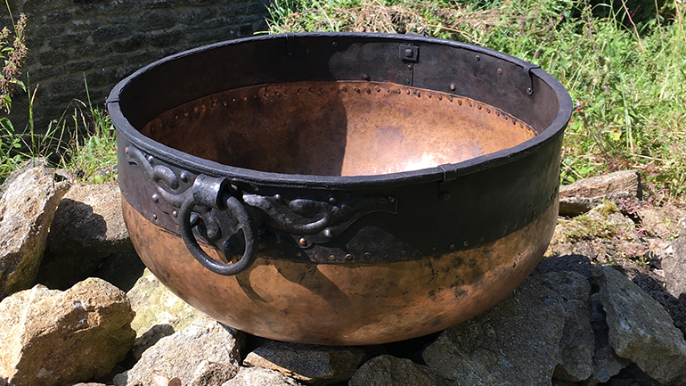 The replica cauldron sitting on some rocks surrounded by grass