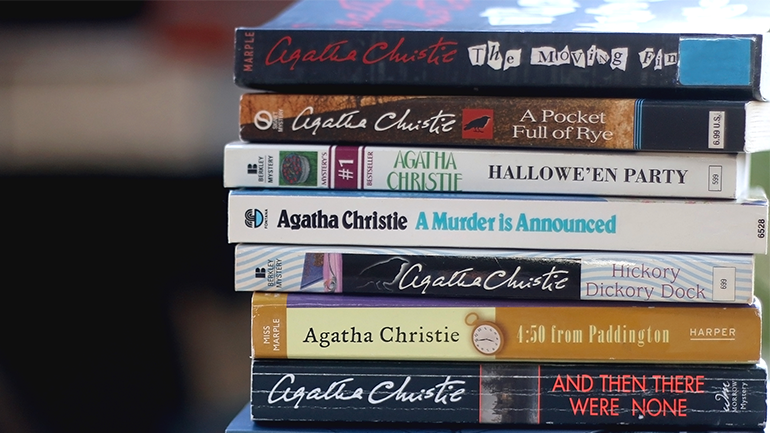 A stack of Agatha Christie books with visible titles including The Moving Finger, A Pocket Full of Rye, Hallowe’en Party, A Murder is Announced, Hickory Dickory Dock, 4:50 from Paddington, and And Then There Were None.